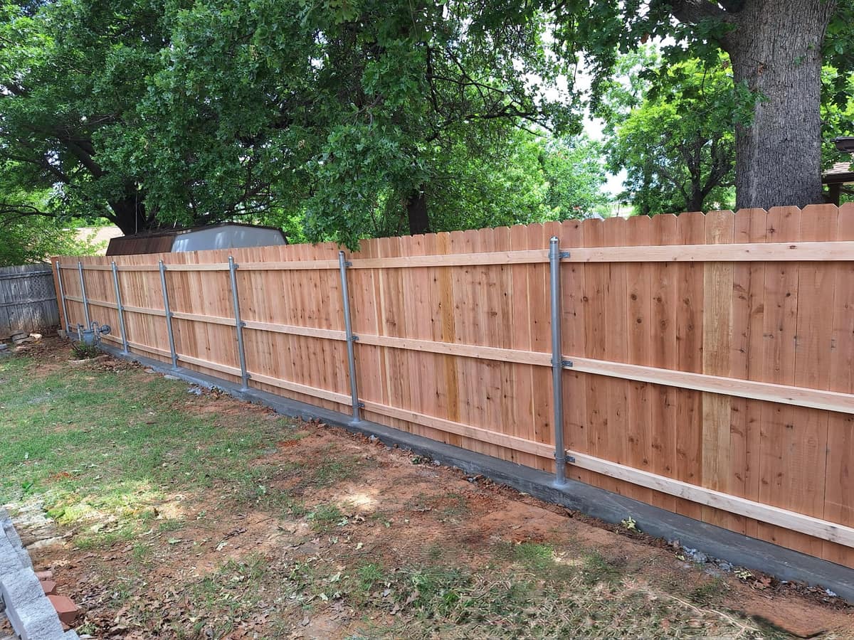 Cedar privacy fence wrapping a green Oklahoma City backyard under a clear blue sky