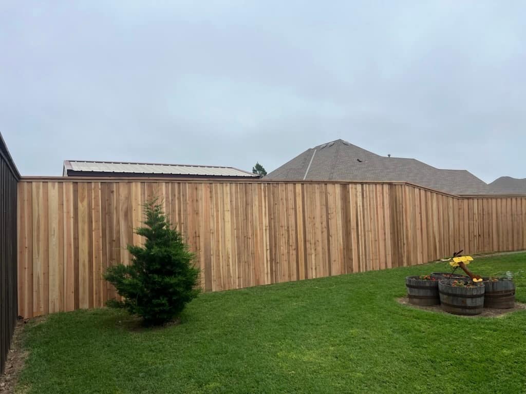 Freshly built cedar privacy fence bordering a landscaped backyard with whiskey-barrel planters
