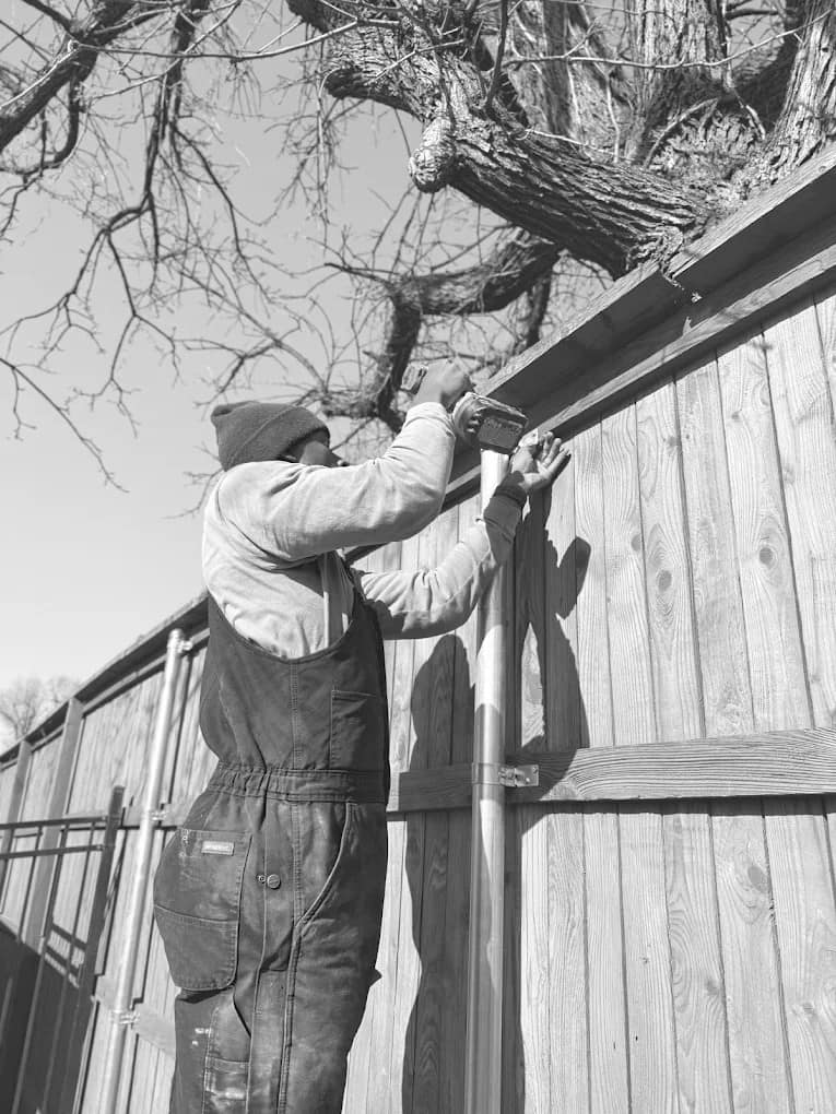 SWY Fencing crew member hand-installing a cedar privacy fence on site — black and white