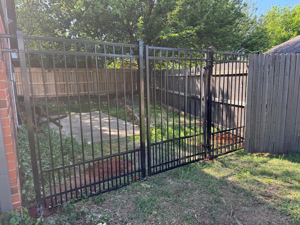 Black ornamental iron fence and matching gate enclosing a residential side yard