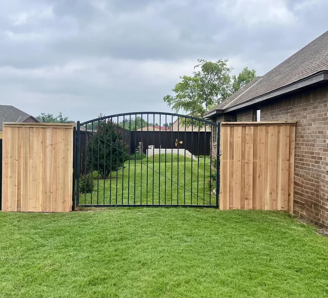 Ornamental iron gate between cedar fence panels